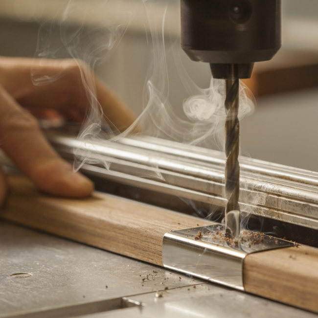 craftsmanship image of drill smoking as it turns on metal bracket shot by Albiston Creative