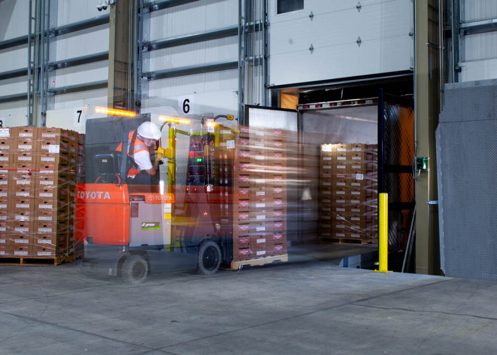 Slow shutter drag image of forklift driver loading truck in warehouse at Deardorff Family Farms.