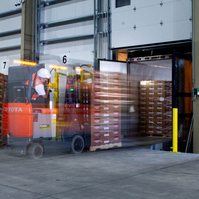 Slow shutter drag image of forklift driver loading truck in warehouse at Deardorff Family Farms.