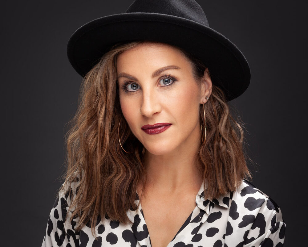 Studio portrait of woman wearing a black hat with a dark neutral background