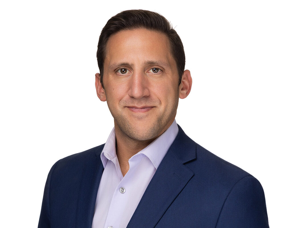 Professional headshot of man wearing a blue suit jacket